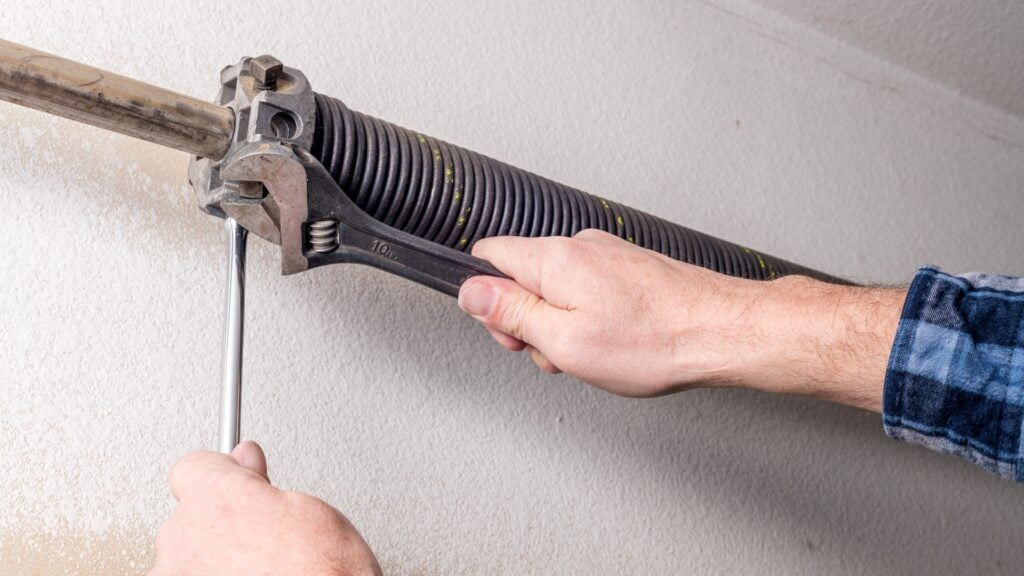 Adjusting garage door torsion spring with spanner