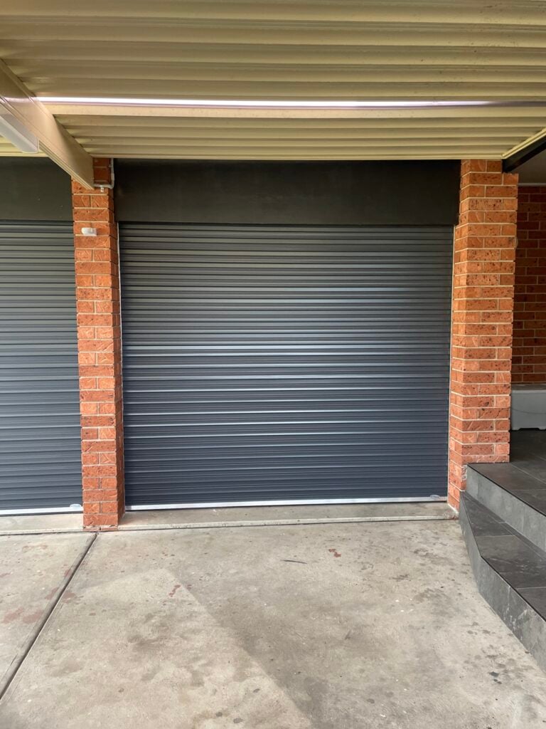 Closed grey roller garage door between brick pillars