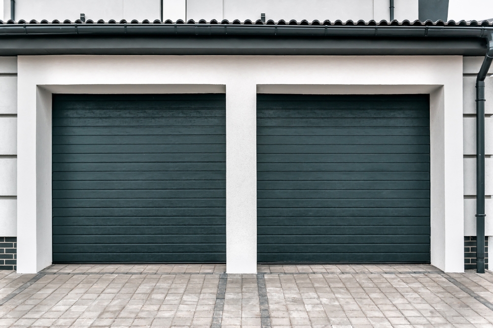 Two dark green garage doors on modern house