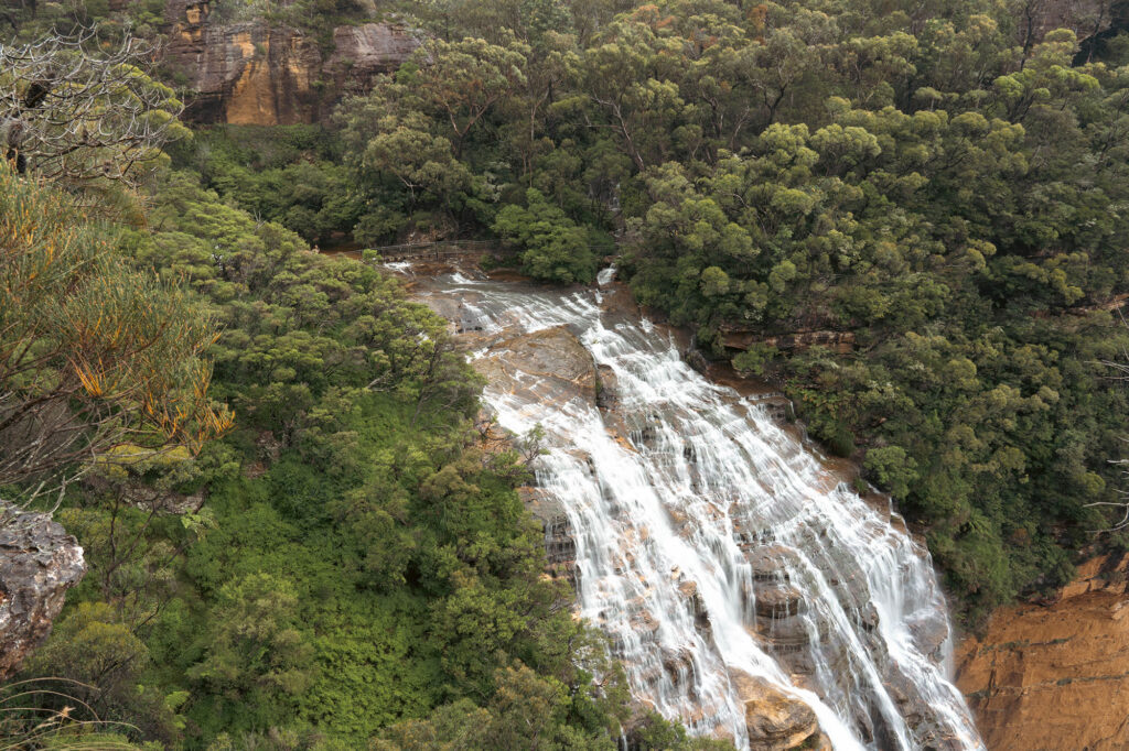 Waterfall cascading over cliff in lush bushland