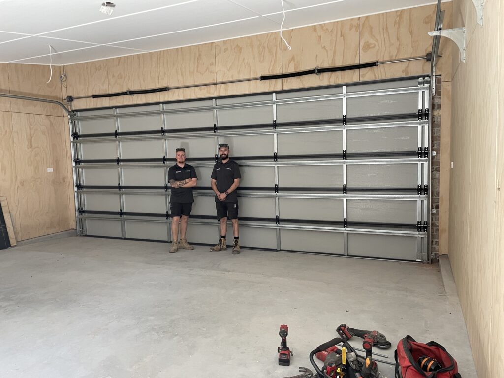 Men standing in a garage with tools.