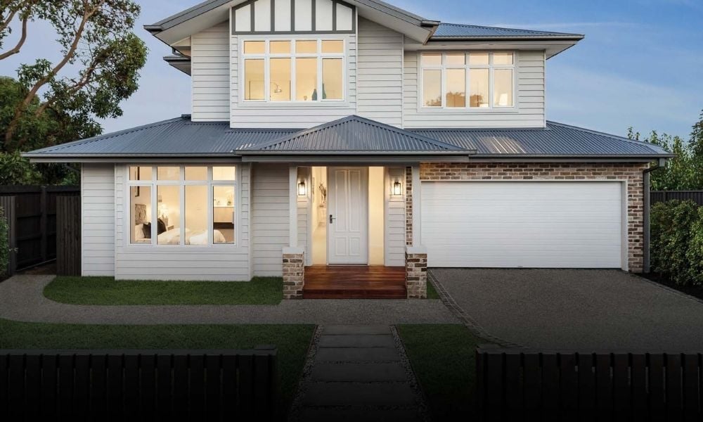 Two-storey home with light cladding, brick accents and a white insulated sectional garage door at the front.