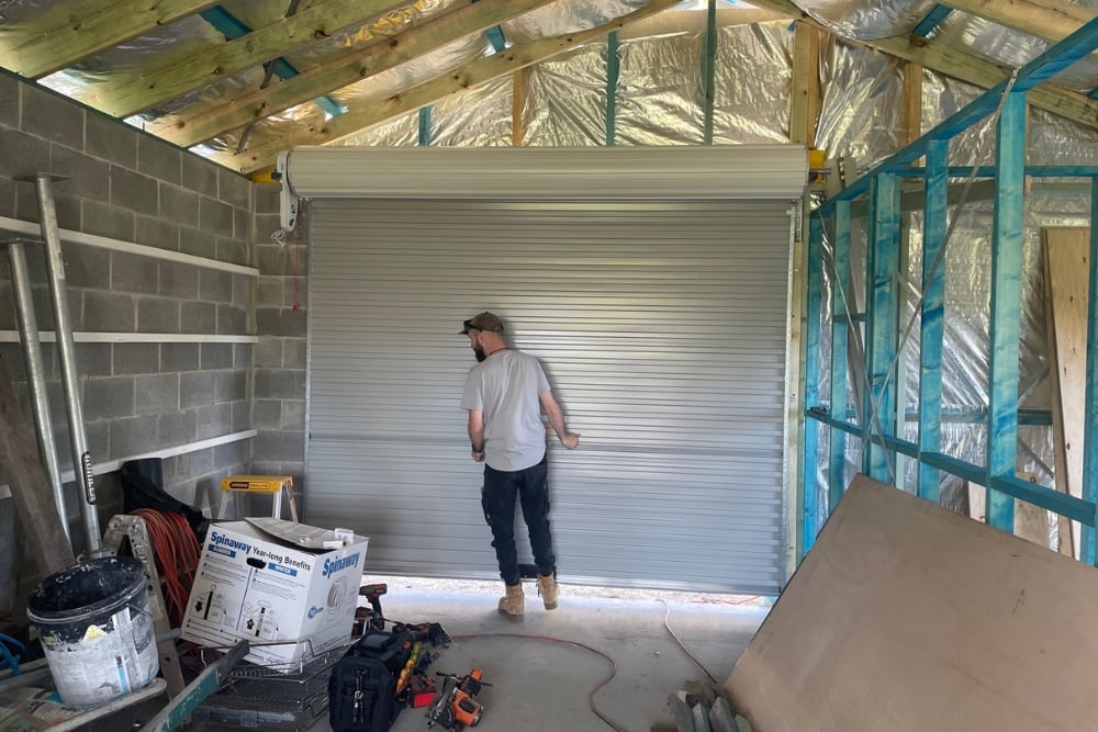 Man installing roller garage door in shed