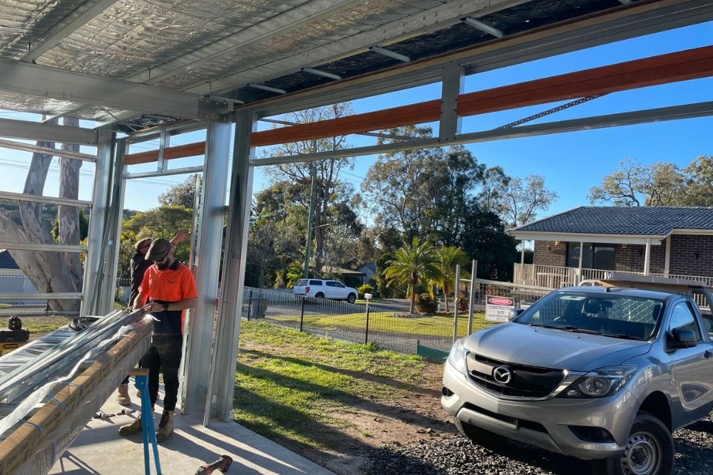 Workers installing steel beam in suburban garage