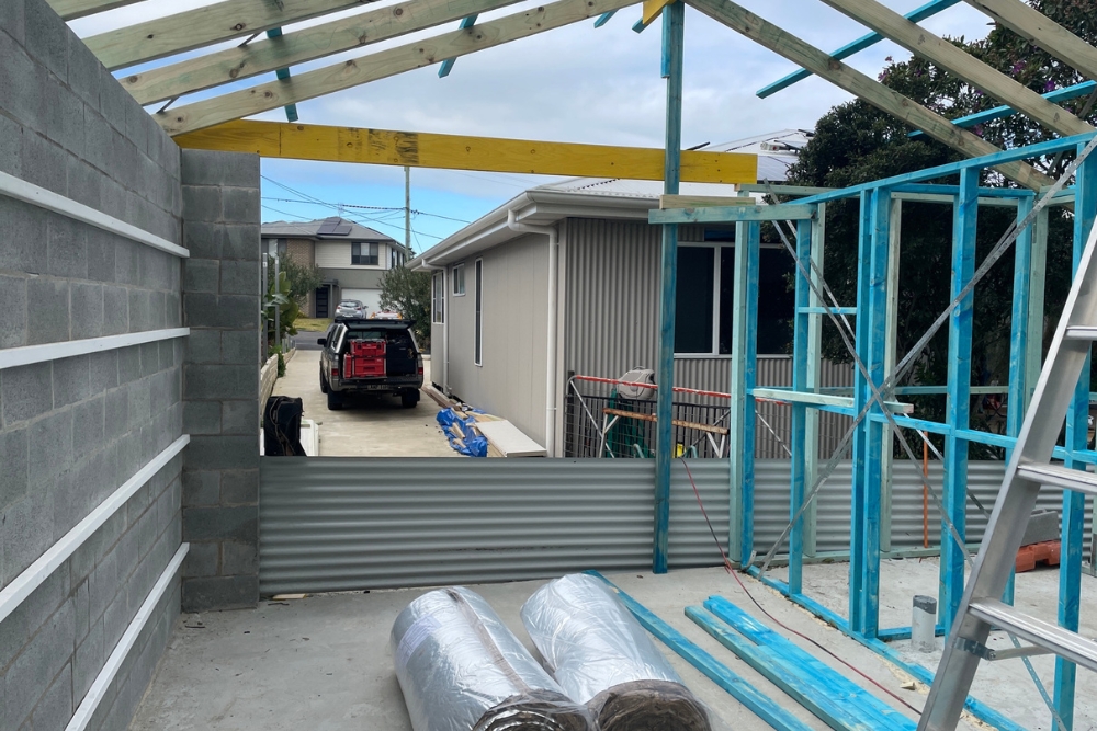 Residential extension framing under construction beside driveway
