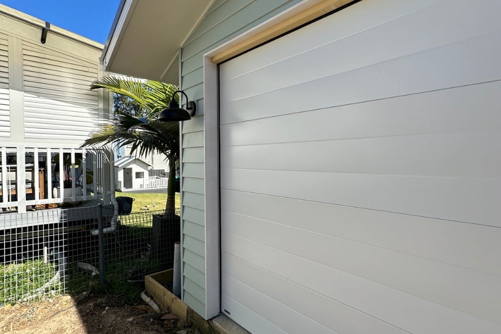 White garage door beside coastal-style home exterior