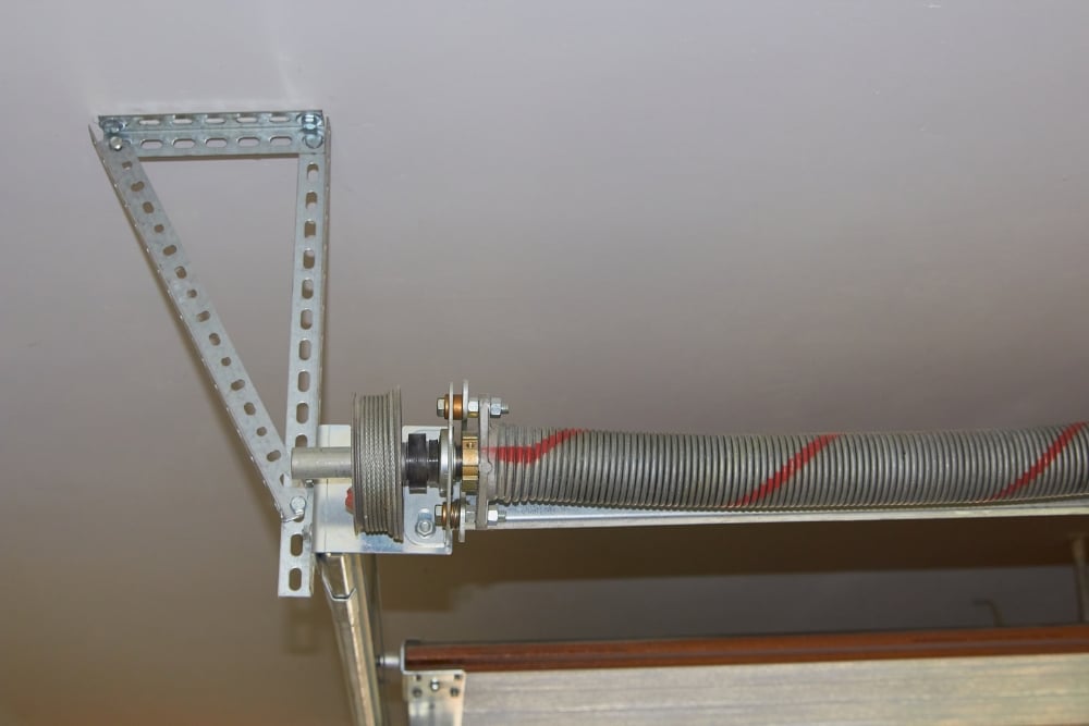 Torsion spring adjustment on insulated sectional garage door