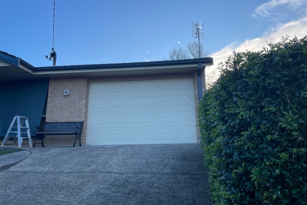 Suburban house garage with driveway and hedge