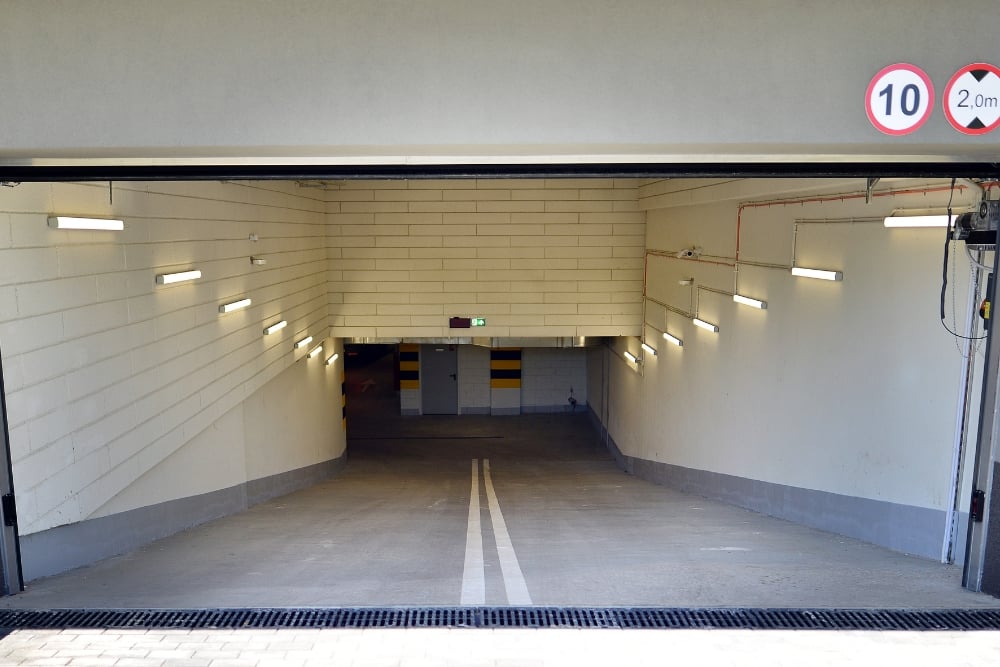 An open underground parking garage entrance with a concrete ramp leading down