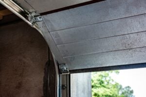 Close-up of the metal hinges, rollers, and tracks on an open sectional garage door.