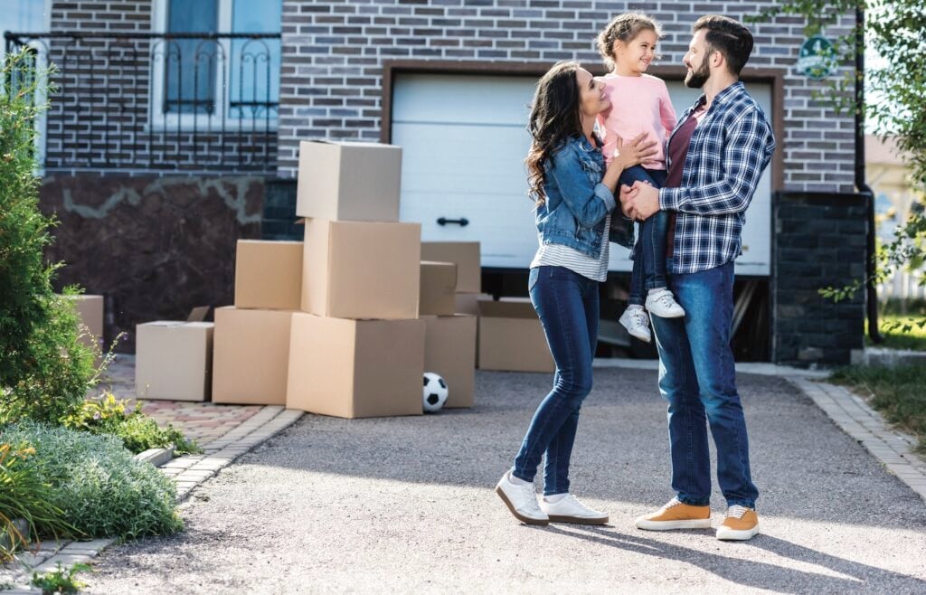 Family with child and moving boxes outside new home