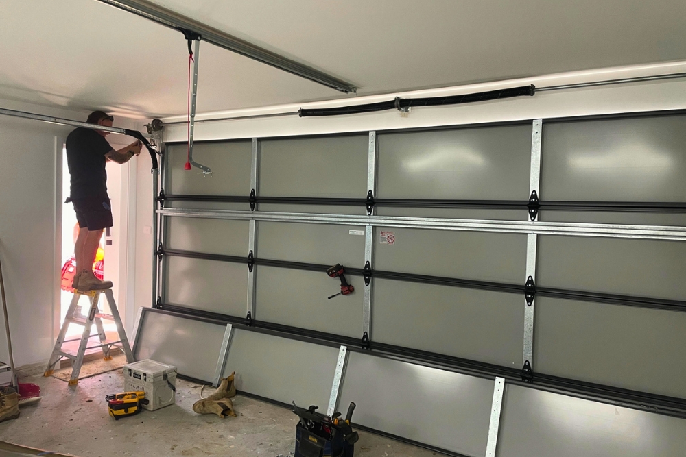 Technician installing sectional garage door inside garage