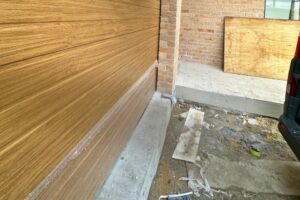 Garage door beside brick wall and debris